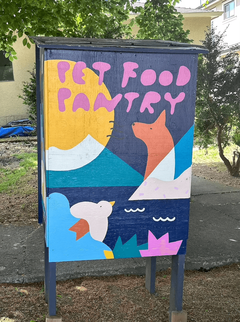 Colorful wooden pet food pantry box featuring a mural with a dog, bird, and sun.